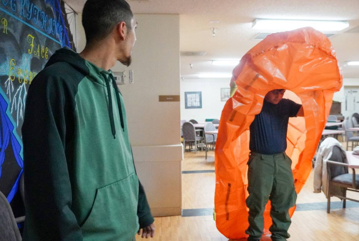 A Wildland Firefighting course participant practices deploying a fire shelter.